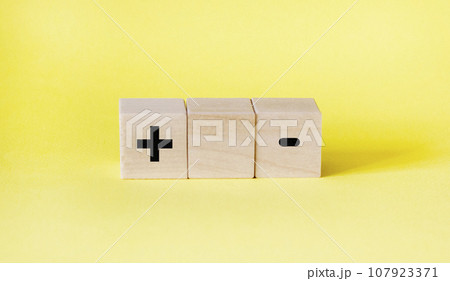 blocks on a yellow background with a plus and a minus. Choice concept blocks on a yellow background with a plus and a minus. Choice concept 107923371
