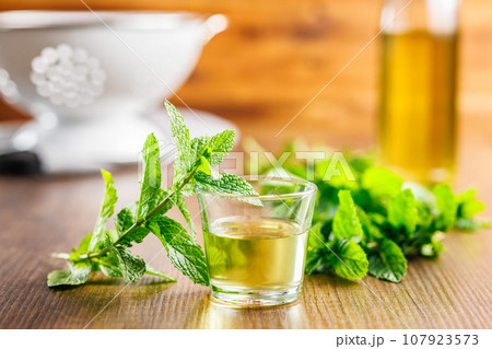 Sweet mint syrup and mint leaves on wooden table. 107923573