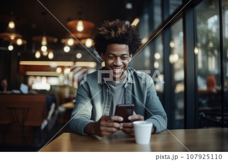 adult african american man works in the office with a smartphone and coffee. positive man working on smartphone, modern technology 107925110