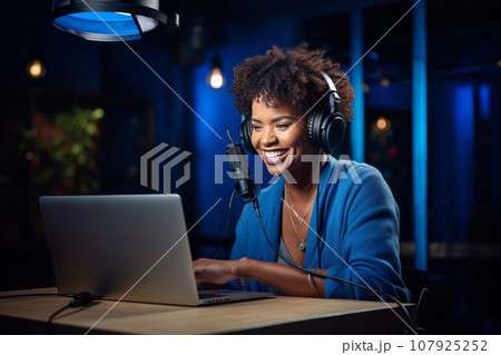 African American woman recording a blog in the studio, wearing headphones in front of a microphone, recording podcasts, blogging African American woman recording a blog in the studio, wearing headphones in front of a microphone, recording podcasts, blogging 107925252