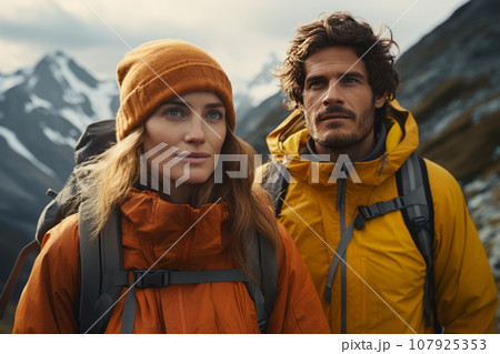 European couple in the mountains against the backdrop of a tent camp, a beautiful couple 35-45 years old in stylish equipment for hiking in the mountains, tourism and vacation concept 107925353
