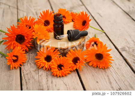 aromatherapy essential oil with fresh marigold flowers on old wooden background. Calendula oil aromatherapy essential oil with fresh marigold flowers on old wooden background. Calendula oil 107926602
