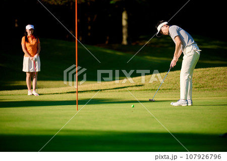グリーン上でパターをするカップル グリーン上でパターをするカップル 107926796