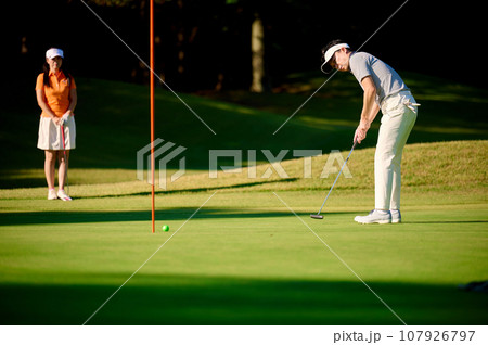 グリーン上でパターをするカップル グリーン上でパターをするカップル 107926797