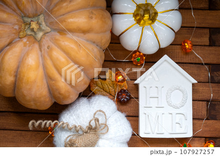 Cozy layout on a wooden background of slats with pumpkins, autumn leaves, a house and keys - autumn mood, Halloween, housing, relocation, mortgage, insurance. Cozy layout on a wooden background of slats with pumpkins, autumn leaves, a house and keys - autumn mood, Halloween, housing, relocation, mortgage, insurance. 107927257