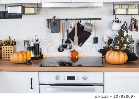 Decor of the white classic kitchen with pumpkins for Halloween and harvest. Autumn mood in the home interior, modern loft style. 107928097