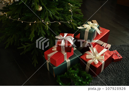 Pile of gift boxes on floor near decorated Christmas tree. Winter holiday celebration concept 107928926