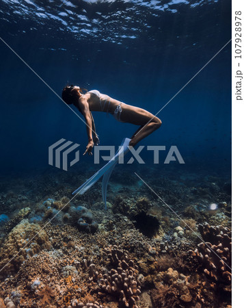 Free diver glides with fins over corals. Freediving or snorkeling in tropical ocean 107928978