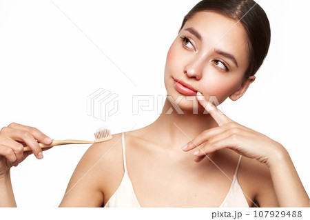 Beautiful young woman brushing her teeth 107929488