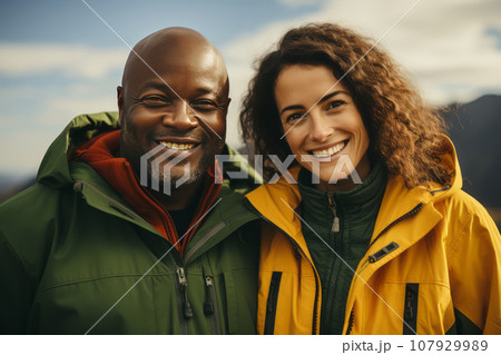 Happy multiracial couple in the mountains against the backdrop of a tent camp. Young international family is engaged in a mountain hike. Active lifestyle, tourism and vacation concept. Happy multiracial couple in the mountains against the backdrop of a tent camp. Young international family is engaged in a mountain hike. Active lifestyle, tourism and vacation concept. 107929989