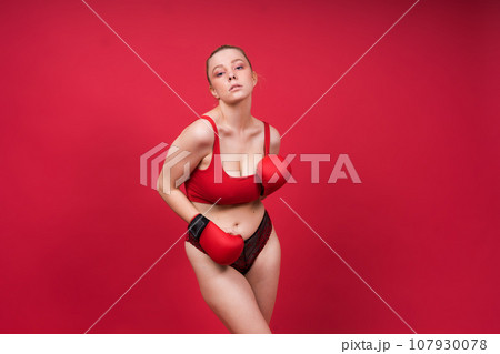 Image of a seductive young woman boxer posing isolated on yellow red background in boxing gloves. 107930078