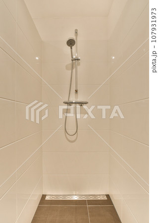 a shower with white tiles on the walls and brown wood flooring in a modern style bathroom area that is clean and ready for a shower with white tiles on the walls and brown wood flooring in a modern style bathroom area that is clean and ready for 107931973
