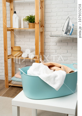Blue plastic laundry basket in a bathroom Blue plastic laundry basket in a bathroom 107933258