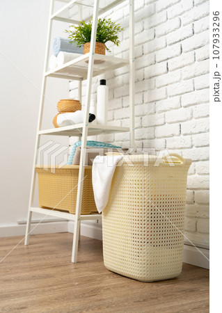 Beige plastic basket for laundry in a room Beige plastic basket for laundry in a room 107933296