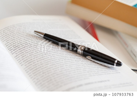 机の上に開いた英語の書籍とペン 研究 学習のイメージ 107933763