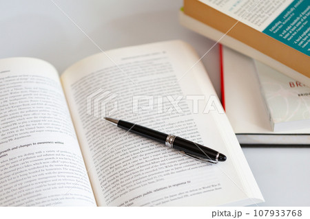 机の上に開いた英語の書籍とペン 研究 学習のイメージ 107933768