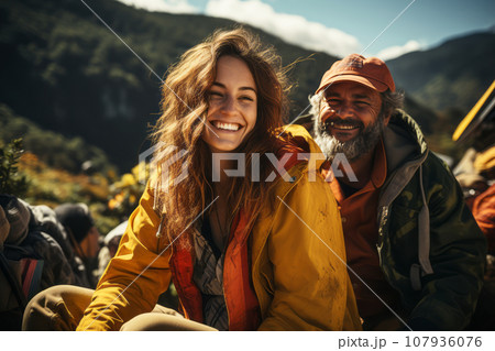 Portrait of happy young couple in the mountains against the backdrop of a tent camp. Caucasian family in bright outwear is engaged in a mountain hike. Active lifestyle, tourism and vacation concept. Portrait of happy young couple in the mountains against the backdrop of a tent camp. Caucasian family in bright outwear is engaged in a mountain hike. Active lifestyle, tourism and vacation concept. 107936076