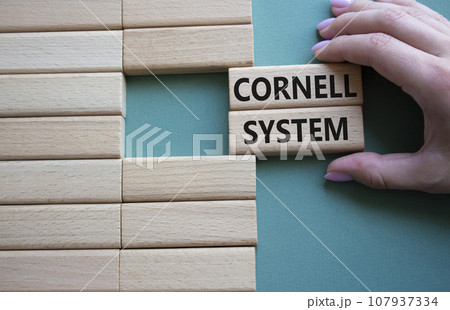 Cornell system symbol. Concept word Cornell system on wooden blocks. Businessman hand. Beautiful grey green background. Business and Cornell system concept. Copy space 107937334