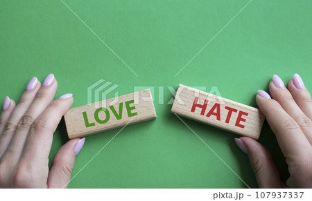 Love vs Hate symbol. Concept word Love vs Hate on wooden blocks. Businessman hand. Beautiful green background. Business and Love vs Hate concept. Copy space Love vs Hate symbol. Concept word Love vs Hate on wooden blocks. Businessman hand. Beautiful green background. Business and Love vs Hate concept. Copy space 107937337