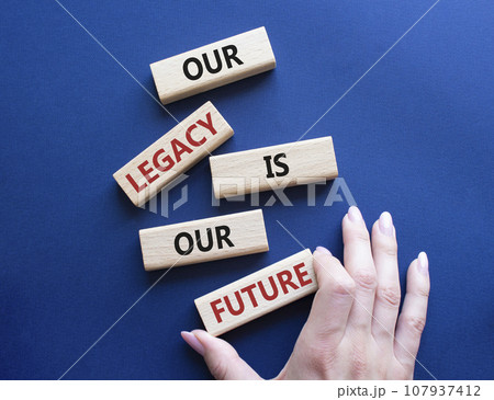Our Legacy is our Future symbol. Concept words Our Legacy is our Future on wooden blocks. Businessman hand. Beautiful deep blue background. Business and Our Legacy is our Future concept. Copy space 107937412