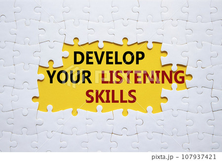 Listening skills symbol. Concept word Develop active listening skills on white puzzle. Beautiful yellow background. Business and Develop active listening skills concept. Copy space 107937421