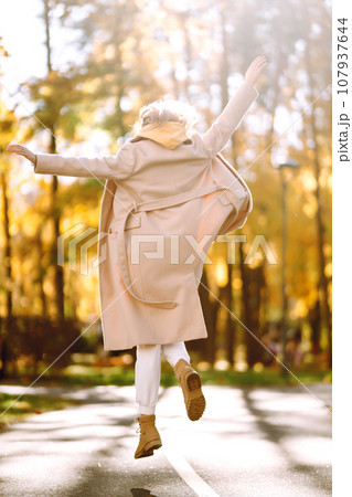 Portrait of a beautiful happy woman with a smile in autumn park. Young girl enjoying rest and freedom 107937644
