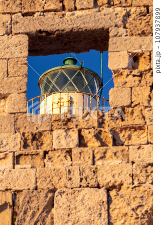 Old stone lighthouse on the breakwater in Rhodes. 107937899