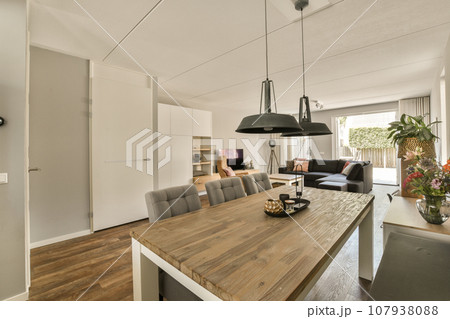 a dining room with wood flooring and white walls in an open living area, including a large wooden table surrounded by grey chairs 107938088
