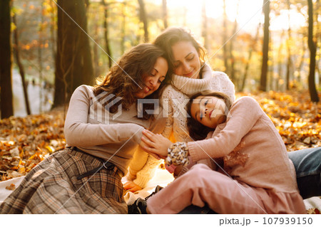 The homosexual family playing with her daughter in the autumn forest. The adventure is more fun. 107939150