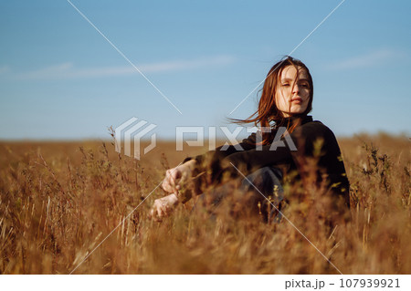 Young woman in stylish clothes posing in autumn field. Nature, fashion, lifestyle. Travel. 107939921