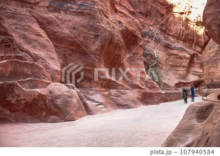 Kayon Sik. Bewin, dressed in traditional clothing, walks along the canyon wall. Petra Jordan 107940584