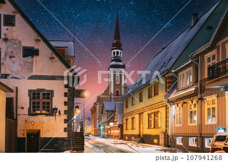 Parnu, Estonia. Night View Of Kuninga Street With Old Houses In Evening Night Illuminations. Amazing Bold Bright Blue Starry Sky Gradient. View Of Lutheran Church Of St. Elizabeth On Background 107941268