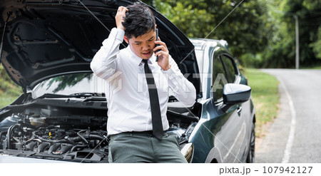 Man calling for help after car breakdown on roadside. Candid shot of businessman waiting for assistance with thumb up. Transportation and insurance concept. Man calling for help after car breakdown on roadside. Candid shot of businessman waiting for assistance with thumb up. Transportation and insurance concept. 107942127