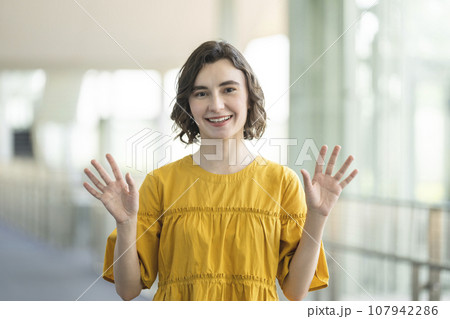カメラ目線で手を振る笑顔の若い外国人女性　 107942286