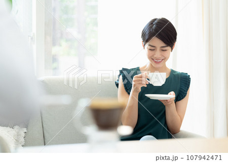 リビングでコーヒーを飲む女性 リビングでコーヒーを飲む女性 107942471