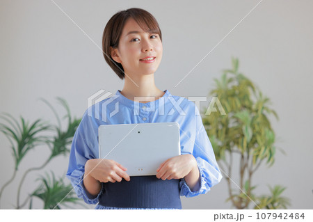 タブレットを胸の前で両手で抱える若い女性1 107942484