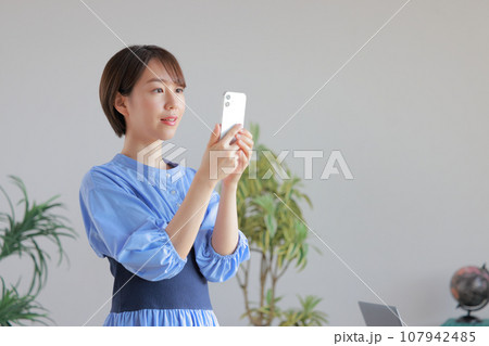 オフィスでスマホを見るショートヘアの若い女性1 107942485