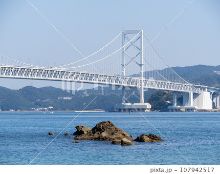 四国側(千鳥ヶ浜海岸)から見た鳴門海峡と大鳴門橋(兵庫県淡路島と徳島県を結ぶ吊橋)。 107942517