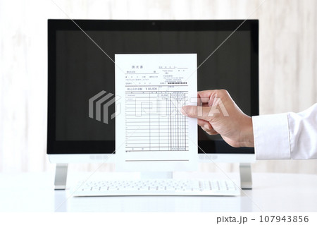 パソコンと請求書を持ったビジネスマンの手 パソコンと請求書を持ったビジネスマンの手 107943856