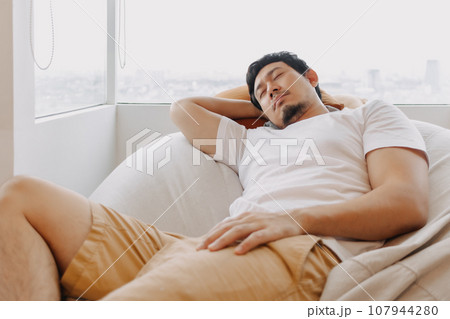 Asian man rest and relaxed on bean bag sofa in the apartment on weekends Asian man rest and relaxed on bean bag sofa in the apartment on weekends 107944280