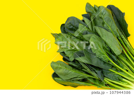 Fresh spinach on yellow background Fresh spinach on yellow background 107944386