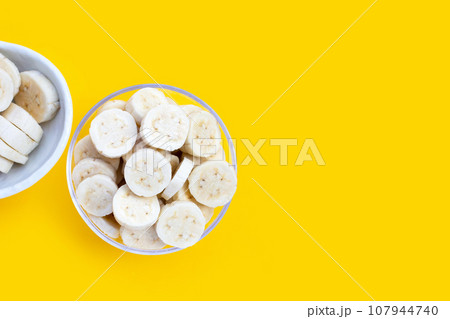 Banana slices in bowl on yellow background. Banana slices in bowl on yellow background. 107944740