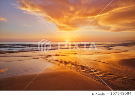 Atlantic ocean sunset with surging waves at Fonte da Telha beach, Costa da Caparica, Portugal 107945094