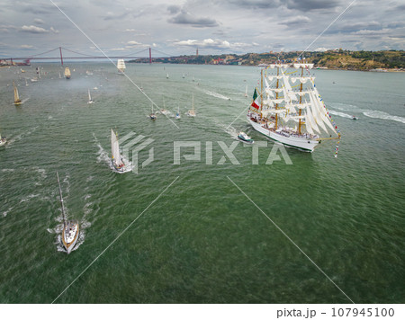 Aerial drone view of tall ships with sails sailing in Tagus river towards the Atlantic ocean in Lisbon, Portugal 107945100