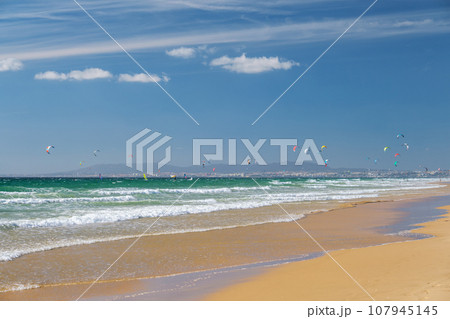 Kiteboarding kitesurfing kiteboarder kitesurfer kites on the Atlantic ocean beach at Fonte da Telha beach, Costa da Caparica, Portugal 107945145