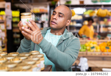 Shopper reads description of canned food at grocery supermarket Shopper reads description of canned food at grocery supermarket 107946202