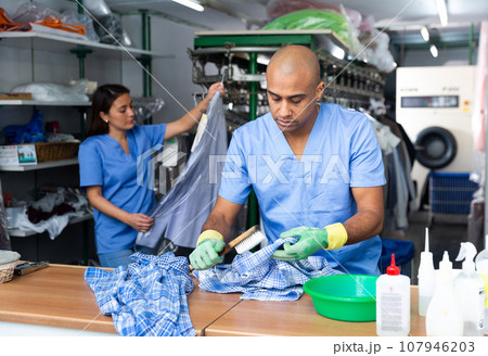 Portrait of male laundry worker examining clean garments 107946203