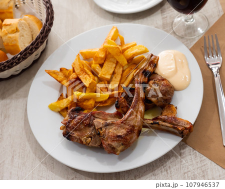 Baked lamb ribs with french fries and aioli sauce Baked lamb ribs with french fries and aioli sauce 107946537