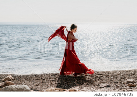 Woman in red dress on sea. Side view a Young...の写真素材 [107946738] - PIXTA