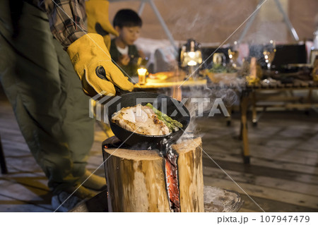グランピング施設でスウェーデントーチで鶏肉を焼く男性手元 グランピング施設でスウェーデントーチで鶏肉を焼く男性手元 107947479